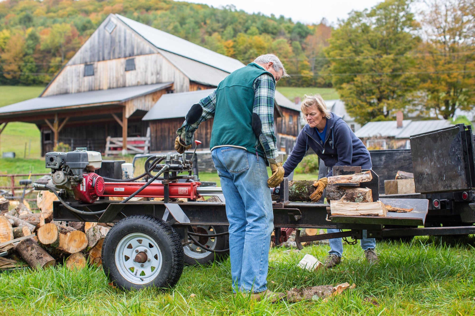 Two people wearing Vermont Glove while stacking wood